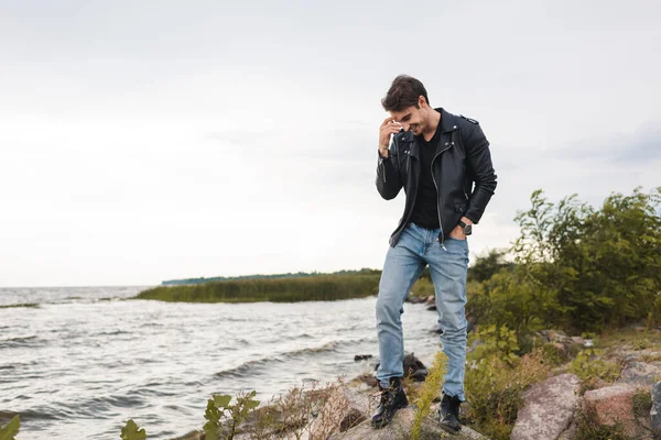 Ung Man Skinnjacka Stående Stenar Nära Havet — Stockfoto