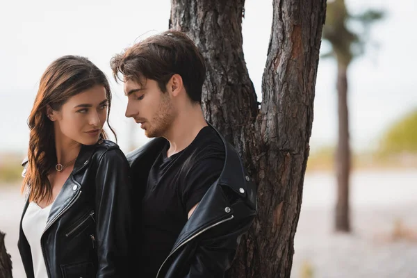 Bruna Donna Guardando Fidanzato Giacca Pelle Vicino Albero Nella Foresta — Foto Stock