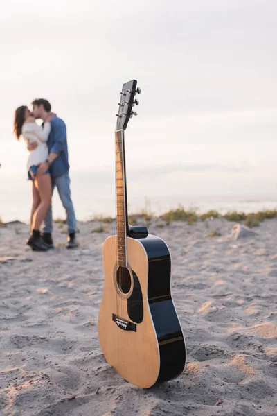 Enfoque Selectivo Guitarra Acústica Arena Pareja Joven Besándose Playa Atardecer — Foto de Stock