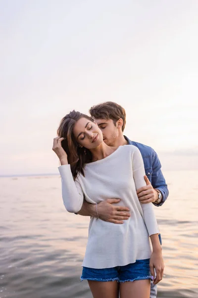 Jovem Beijando Pescoço Abraçando Mulher Morena Perto Mar — Fotografia de Stock