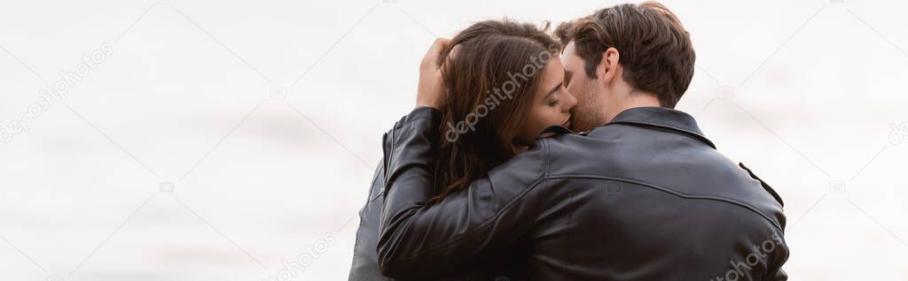 Panoramic shot of man kissing girlfriend near sea 