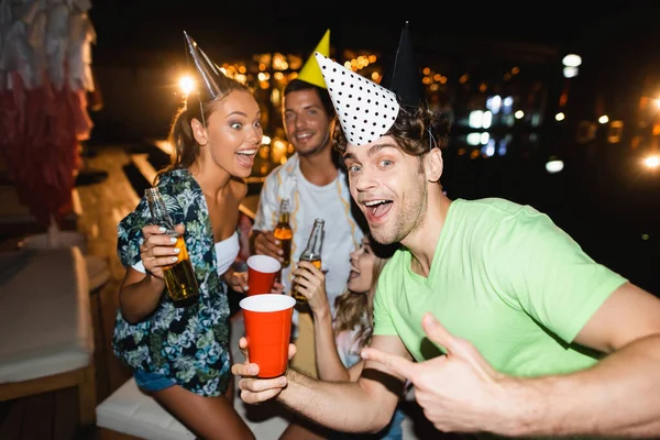 Selective Focus Man Party Cap Pointing Disposable Cup Friends Night — Stock Photo, Image