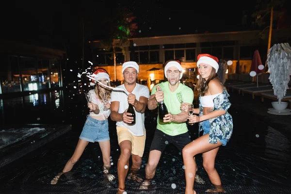 Enfoque Selectivo Amigos Sombreros Santa Apertura Champán Piscina Por Noche — Foto de Stock