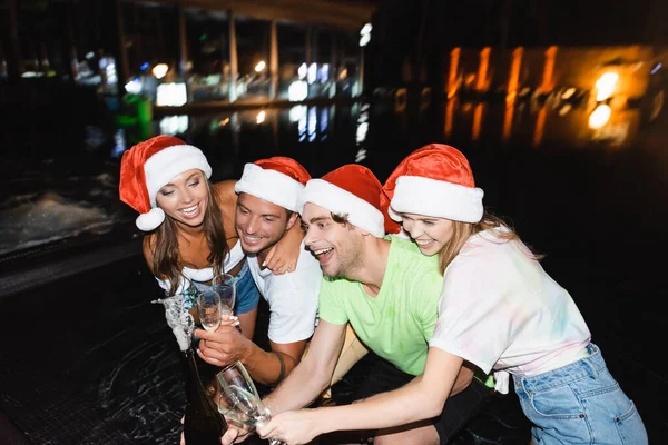 Friends Santa Hats Opening Bottle Champagne While Celebrating New Year — Stock Photo, Image