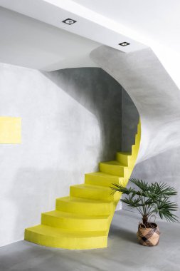 Beton duvarları ve fabrika yakınında sarı merdivenleri olan modern iç mekan.