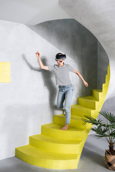 Женщина в гарнитуре виртуальной реальности спускается по лестнице 