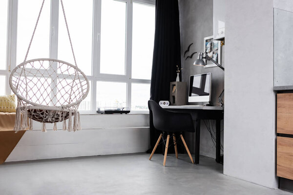 Spacious workplace interior with computer and hanging chair