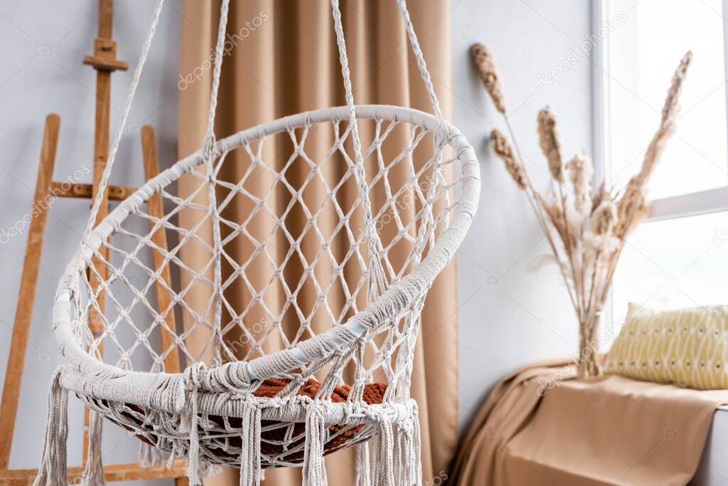 Modern studio interior with hanging chair and easel