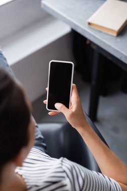 Evde boş ekranlı akıllı telefon kullanan genç bir kadının genel görünümü 