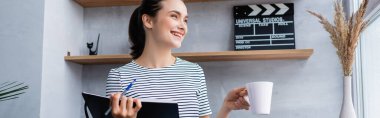 Not defteri, kalemi ve fincanı olan esmer kadının oturma odasındaki pencereye baktığı web sitesi başlığı 