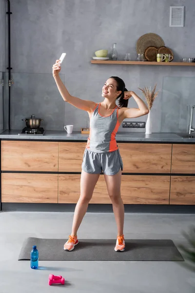 Sporcu Kadının Evde Spor Aletleri Şişesinin Yanındaki Akıllı Telefondan Selfie — Stok fotoğraf