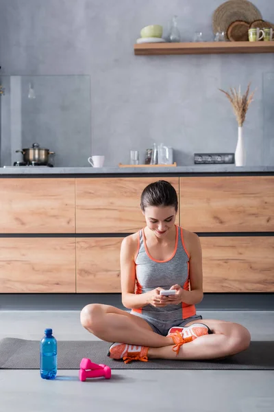 Sportswoman Using Smartphone Fitness Mat Dumbbells Bottle Water Home — Stock Photo, Image