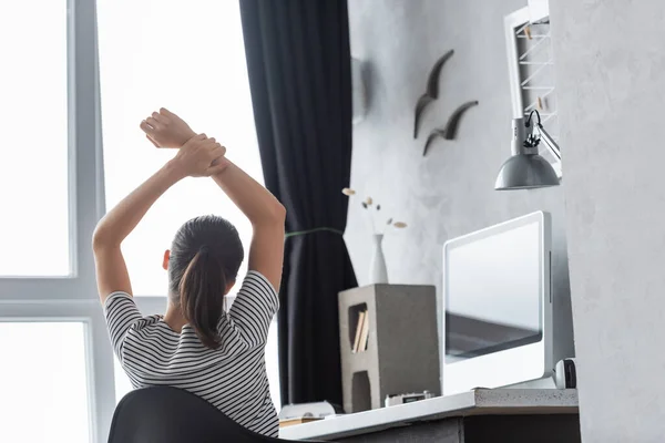 テーブルの上にコンピュータの近くに座っている若いテレワーカーのバックビュー — ストック写真