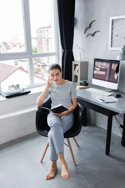 Barefoot Freelancer Κοιτάζοντας Σημειωματάριο Ενώ Εργάζονται Κοντά Ψηφιακές Συσκευές Στο — Φωτογραφία Αρχείου