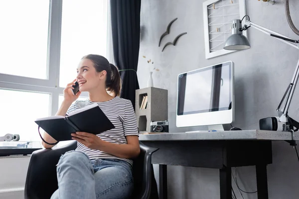 Selective Focus Young Freelancer Holding Notebook While Talking Smartphone Home — Stock Photo, Image