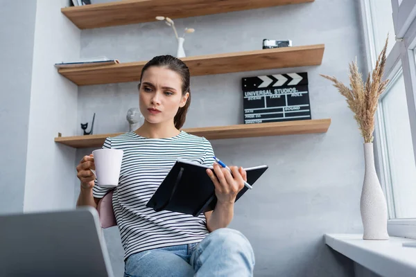 Selective Focus Thoughtful Freelancer Holding Notebook Cup While Looking Laptop — Stock Photo, Image