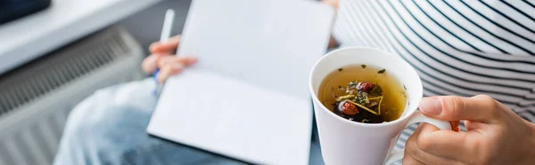 Panoráma Felvétel Kezében Csésze Gyógynövény Tea Notebook Otthon — Stock Fotó