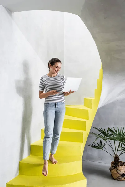 Young Woman Using Laptop While Walking Stairs Home — Stock Photo, Image