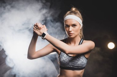 Arka planda dumanı olan sımsıkı elleri olan sporcu kadının ön görüntüsü