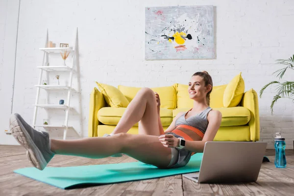 Lächelnde Frau Fleckt Auf Fitnessmatte Neben Laptop Und Sportflasche — Stockfoto