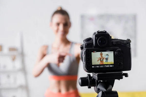 Selektiver Fokus Der Lächelnden Sportlerin Die Auf Sportflasche Neben Digitalkamera — Stockfoto