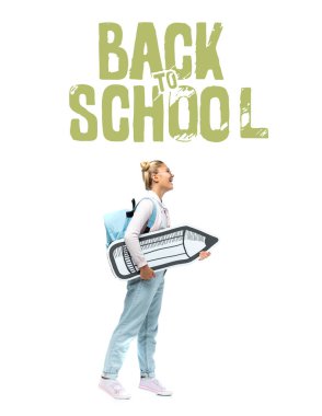 Sırt çantalı çocuk elinde kağıt kalemle okula geri dönüyor. 