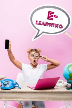 Liseli kız elinde büyüteç ve akıllı telefon ile konuşma baloncuğunun yanında pembe harfler, dünya ve dizüstü bilgisayarı olan boş bir ekran tutuyor. 