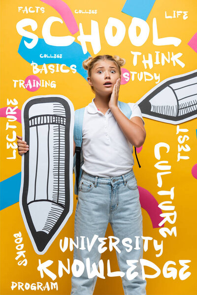 Worried schoolchild with backpack and paper pencil looking at camera near lettering on yellow 