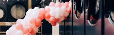 Modern çamaşır makinelerinin yanındaki pembe balonlar çamaşırhanede, pankartta