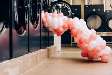 Modern çamaşır makinelerinin yanında pembe balonlar.