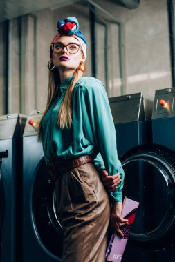 Kamu çamaşırhanesinde gözlüklü ve türbanlı moda bir kadın. 