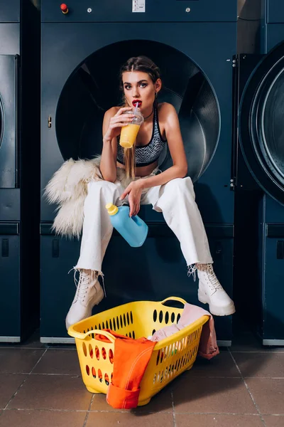 Stylish Woman Sitting Washing Machine Faux Fur Jacket Drinking Orange — Stock Photo, Image