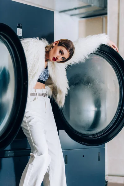 Young Stylish Woman Faux Fur Jacket Standing Washing Machines Public — Stock Photo, Image