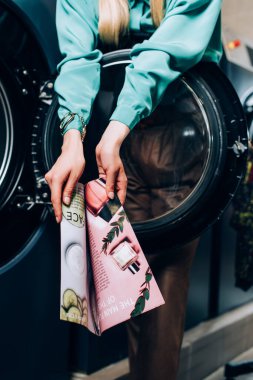 Çamaşırhanede elinde dergi tutan genç bir kadının kırpılmış görüntüsü 