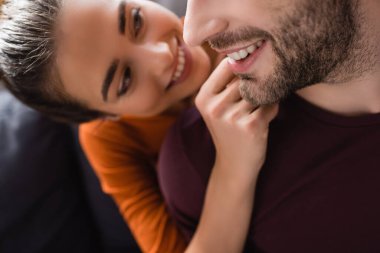 smiling woman touching face of happy man on blurred background clipart