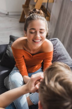 Neşeli kadın, sevgili adama bakıyor. Önplanda ellerini öpüyor.