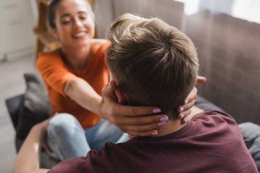 back view of man near happy woman embracing his neck on blurred background clipart