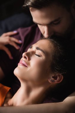 Depresyondaki kadını sakinleştiren ve başını öpen genç adam.