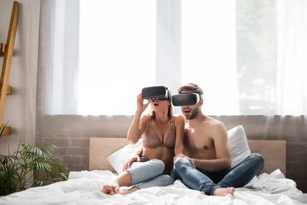 Opgewonden Jong Paar Met Behulp Van Headsets Terwijl Zitten Bed — Stockfoto