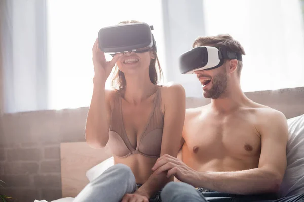 Excited Woman Touching Headset Shirtless Boyfriend Bedroom — Stock Photo, Image