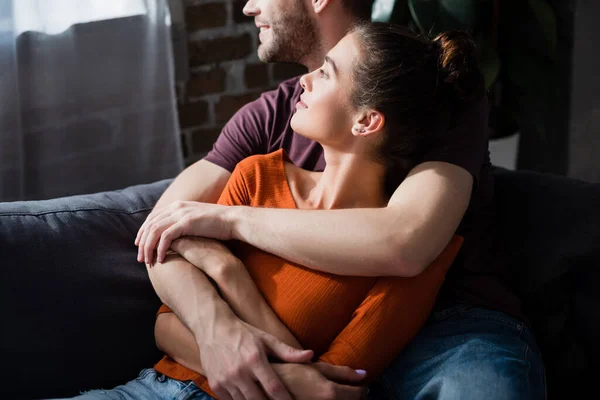 Feliz Joven Pareja Abrazando Mientras Relaja Sofá Mirando Hacia Otro — Foto de Stock