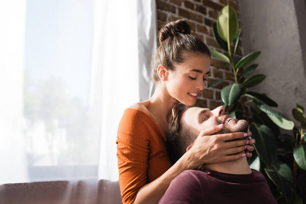 нежная женщина трогает лицо любимого мужчины с закрытыми глазами