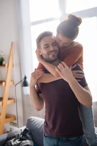 Young Woman Hugging Boyfriend Back While Standing Sofa Home — Stock Photo, Image