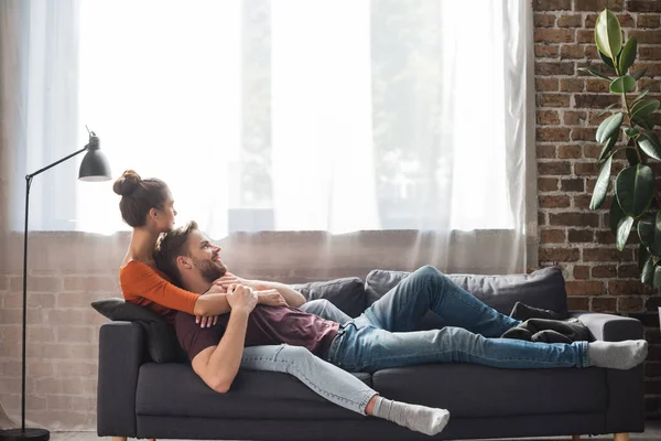 Junges Paar Entspannt Auf Sofa Neben Fenster Hause — Stockfoto