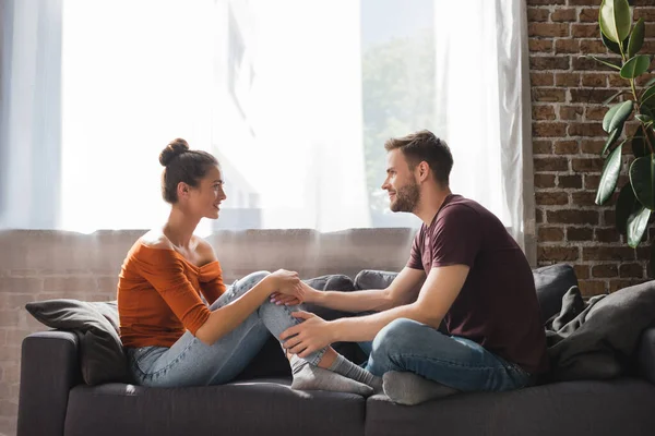 Vista Lateral Jovem Casal Conversando Enquanto Sentado Sofá Mãos Dadas — Fotografia de Stock