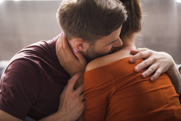 Нежный молодой человек обнимает молодую девушку, прикасаясь к его шее