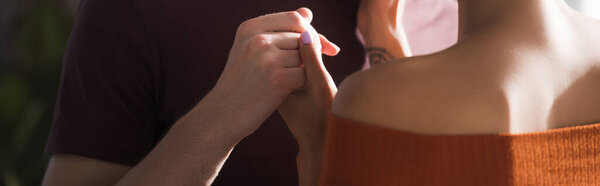 обрезанный вид мужчины, держащегося за руки любимой женщины, знамя