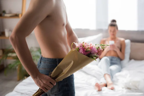 Shirtless Man Holding Bouquet While Girlfriend Chatting Smartphone Blurred Background — Stock Photo, Image