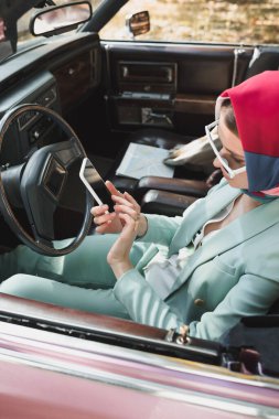 Elegant woman using smartphone on driver seat of roofless car  clipart