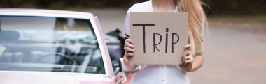 Kırpılmış arka plan, bulanık pankart ve pankartta eski model Cabriolet 'in yanında trip harfleri olan kadın görüntüsü.